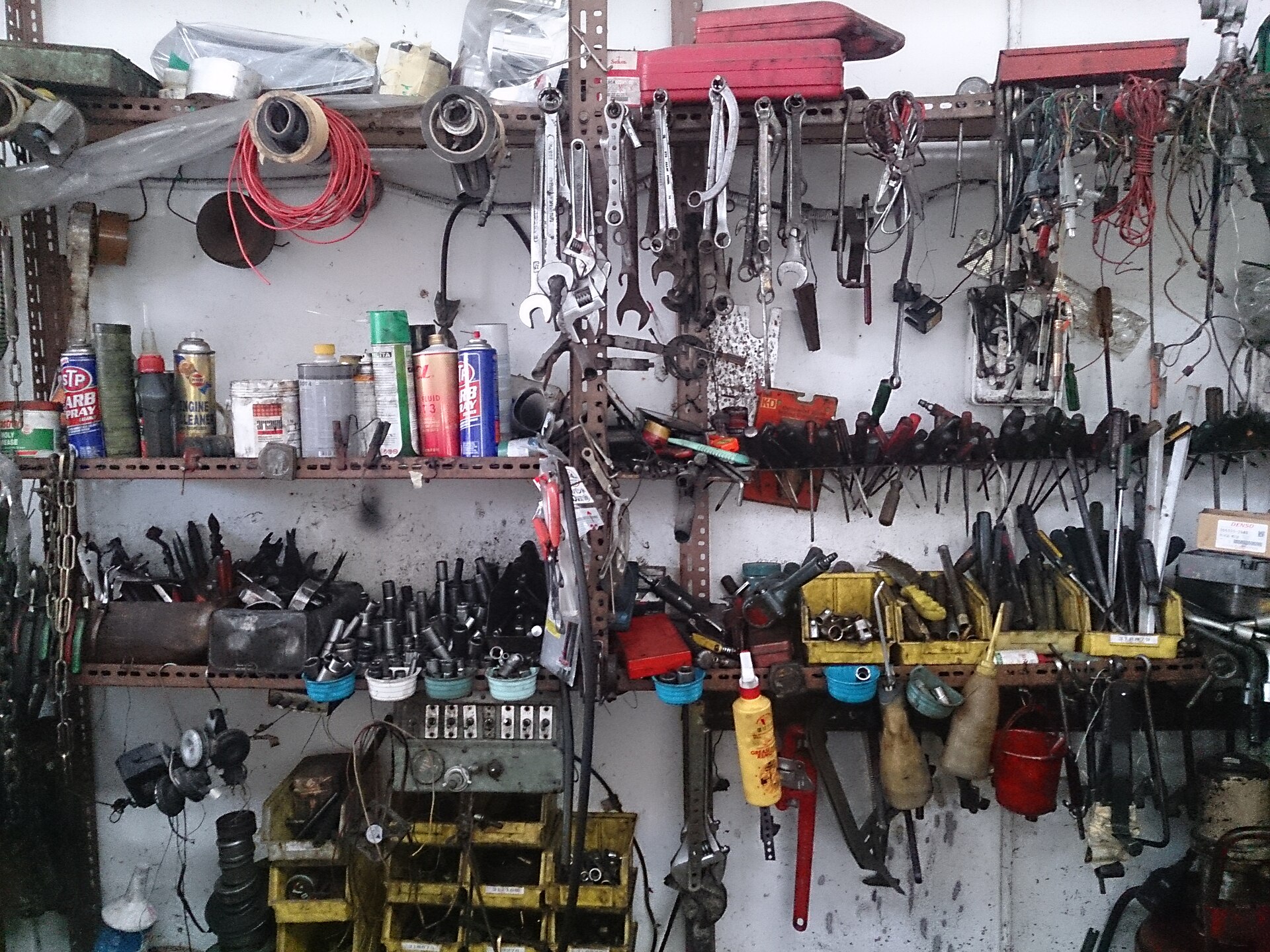 Un mur d'atelier mécanique couvert de clés, de pinces et d'outils rangés sur des étagères